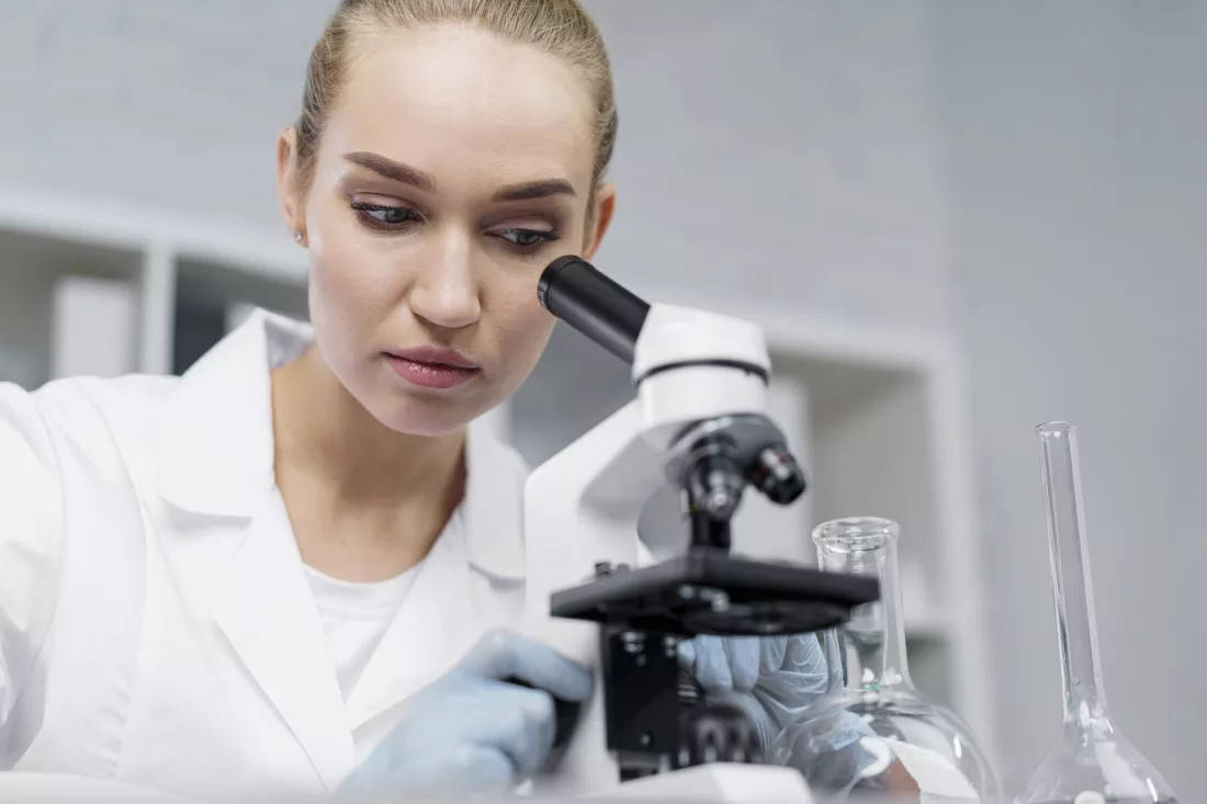 Młoda badaczka w laboratorium patrzy w mikroskop